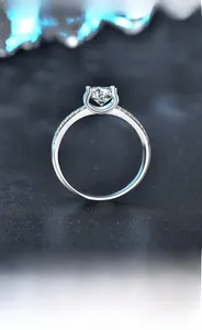 Macro shot of a classic moissanite silver ring with double-row side stones on black texture