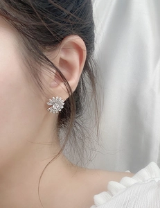 Close-up of sparkling daisy flower earring with moissanite stones on a person's ear