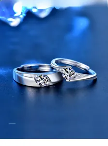 Macro view of couple's silver rings with 3EX cut moissanite on blue textured background
