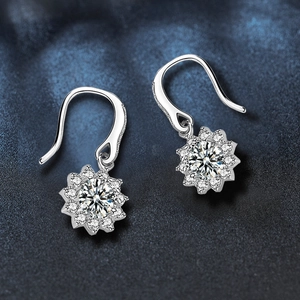 Makroaufnahme von Silbernen Sonnenblumen-Ohrringen mit Moissanit-Steinen auf Blau