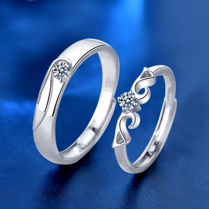 Close-up of S925 silver wing-themed couple rings with brilliant diamonds on blue background