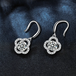 Macro shot of silver four-leaf clover drop earrings with round-cut sparkling stones