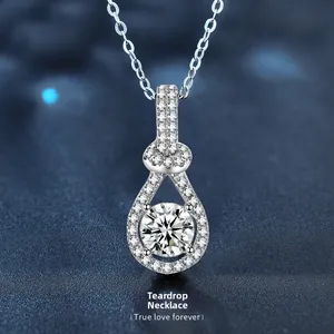 Macro shot of silver teardrop pendant necklace with pavé diamonds on dark blue background