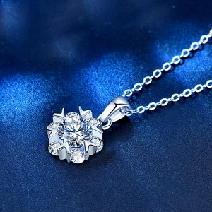 Macro view of snowflake pendant with moissanite center on a shiny silver chain