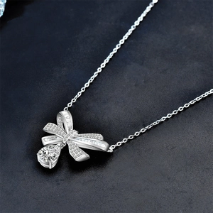 925 silver necklace with bow pendant and teardrop moissanite stone on black background