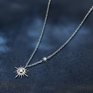 Elegant silver sunburst moissanite necklace with sparkling stones on blue starry background