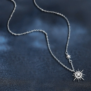 Moissanite sunburst necklace in sterling silver with star charm on a starry blue background