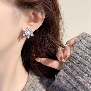 Sparkling S925 sterling silver snowflake stud earrings worn by a model in soft lighting