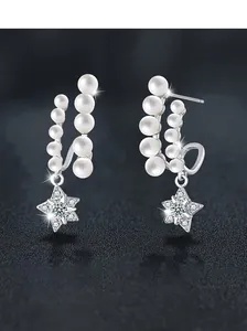 Close-up of S925 silver star earrings with curved pearls and sparkling pavé moissanite