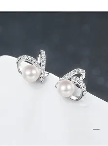 Macro view of S925 silver pearl earrings with Moissanite pavé and interlocking arc design
