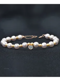 Dettaglio del bracciale di perle e sfere dorate con ciondolo di diamante solitario lucido