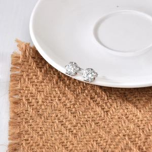 Classic six-prong S925 sterling silver stud earrings with round moissanite on a ceramic dish
