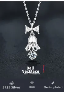 Macro detail of S925 silver bell pendant with moissanite and bowknot on dark background