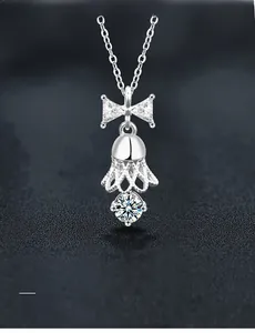 Macro shot of S925 silver bell pendant with bow design and shimmering moissanite stones