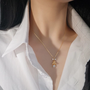 Golden S925 silver bell necklace with sparkling bow pendant worn by a female model