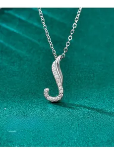 Close-up of S925 silver moissanite necklace with J-shaped pendant on green velvet
