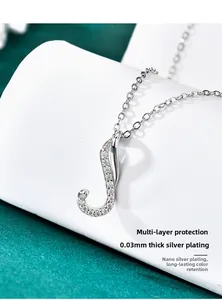 Macro detail of J-shaped silver pendant showing 0.03mm plating and pavé set moissanite stones