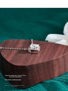 Close-up of square moissanite pendant with S925 silver four-prong setting on wood base