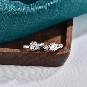 S925 sterling silver couple rings with moissanite stones on elegant wooden tray