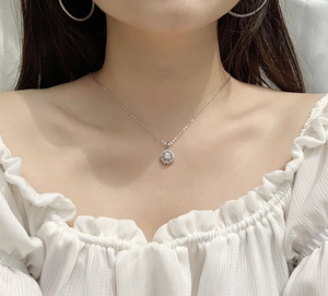 Gros plan du collier fleur en argent S925 avec moissanite porté par un mannequin chic