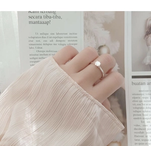 Close-up of classic six-prong solitaire moissanite ring worn on hand with elegant sleeve