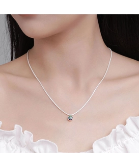 Detail of sterling silver crown necklace featuring a vibrant moissanite with rainbow fire
