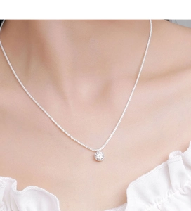 Close-up of sparkling moissanite crown necklace on neck with silver woven chain