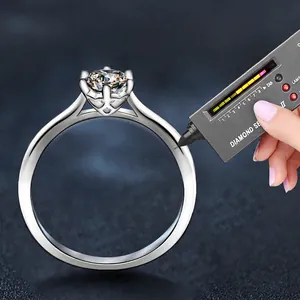Moissanite ring with six-prong setting tested with a diamond selector pen on blue surface