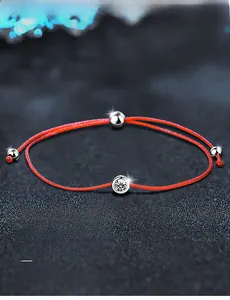 Detail of red braided cord bracelet featuring a 3EX cut moissanite with 58 facets