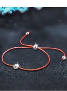 Macro detail of red woven cord bracelet with nano silver plated beads and zircon stone