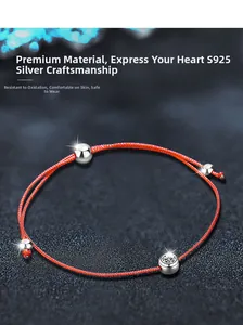 Macro detail of S925 sterling silver beads on a minimalist woven red cord bracelet