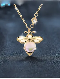 Macro detail of golden bee pendant with iridescent pearl and sparkling zircons