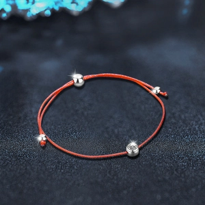 Minimalist red cord bracelet with 925 silver beads and moissanite stone on dark background