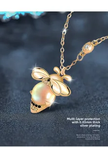 Macro shot of 925 silver bee pendant with moonstone and gold-plated details