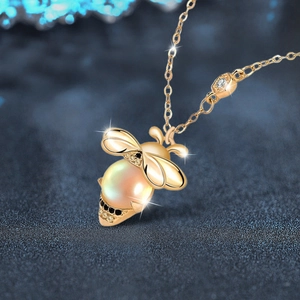Elegant gold bee pendant necklace with moonstone pearl and zircon stones on a dark background