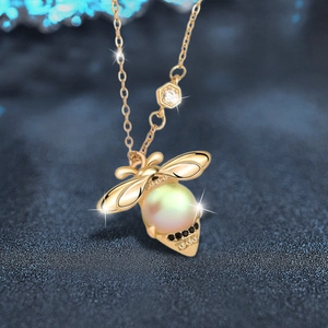 Golden bee necklace with moonstone and pearl pendant on dark blue background