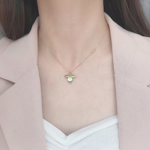 Elegant gold bee pendant necklace with moonlight gemstone worn by a model in pink suit