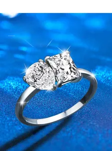 Macro detail of S925 sterling silver ring with pear and emerald cut stones on blue background