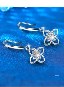Macro shot of silver clover earrings with sparkling center stones on a glitter background