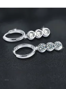 Vue macro de boucles d'oreilles en argent S925 avec trois pierres de moissanite brillantes