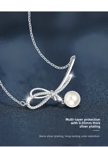 Macro shot of 925 silver bow pendant with sparkling moissanite and a round pearl