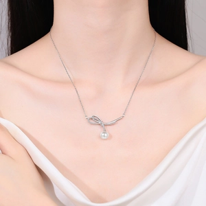 925 silver bow necklace with elegant white pearl pendant on a silk fabric background