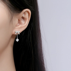 Elegant 925 sterling silver bow earrings with hanging round zircon pendant on model