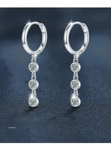 Close-up of 925 silver tassel earrings with 3EX cut moissanite stones on blue background