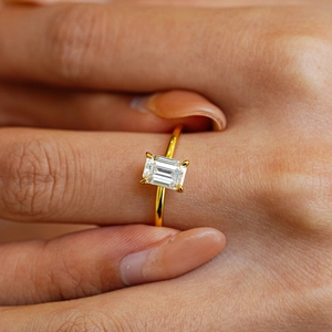 Classic emerald cut moissanite ring with four-prong setting on 18k gold band