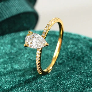 Pear cut moissanite ring with 18K gold plating and pave diamonds on velvet background
