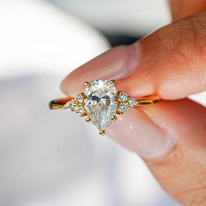 Pear-cut moissanite halo ring in 18K gold plated S925 silver worn on a finger