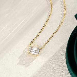 Close-up of emerald cut moissanite pendant on a 14K gold plated silver cross chain
