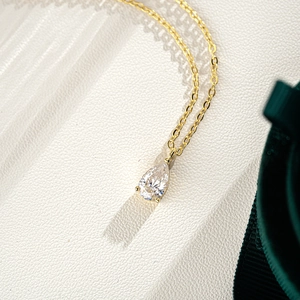 Close-up of 1 carat pear cut moissanite pendant with 3-prong setting on gold chain