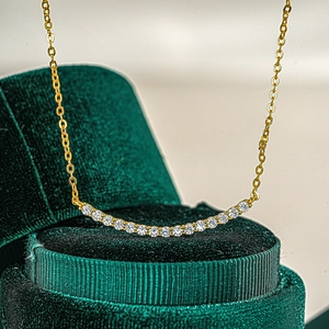 S925 sterling silver smile necklace with 1 carat moissanite stones on green velvet